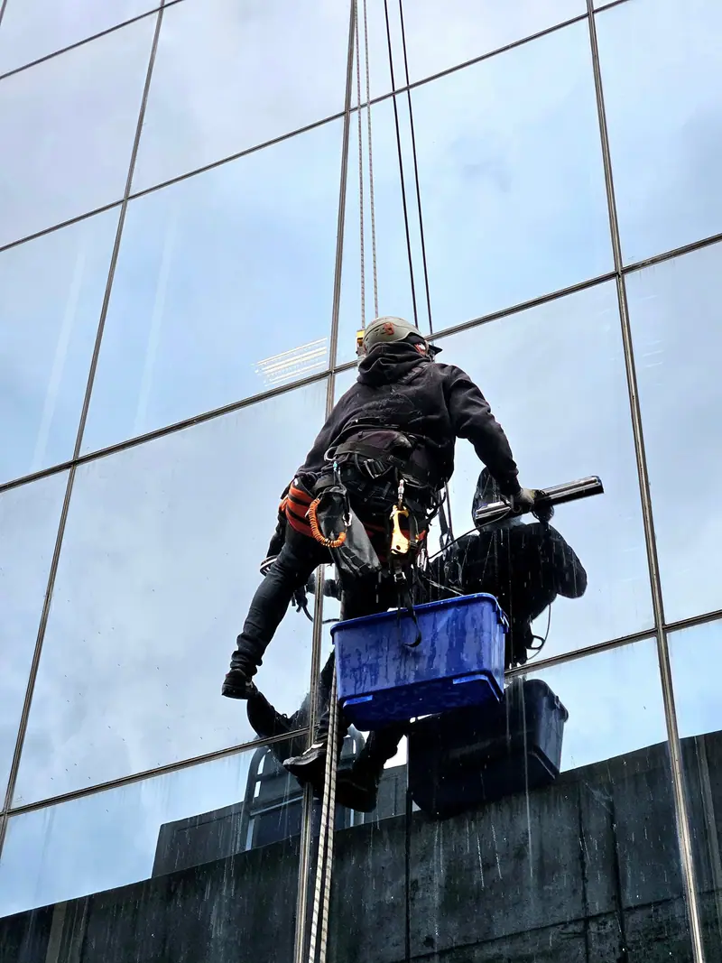 ProClimb technician cleaning a glass facade on rope access