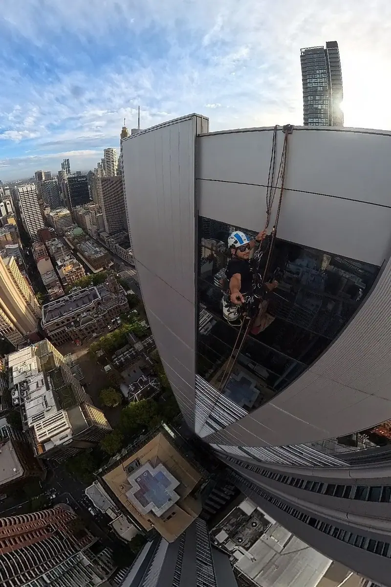 Technician working on a facade high above the city