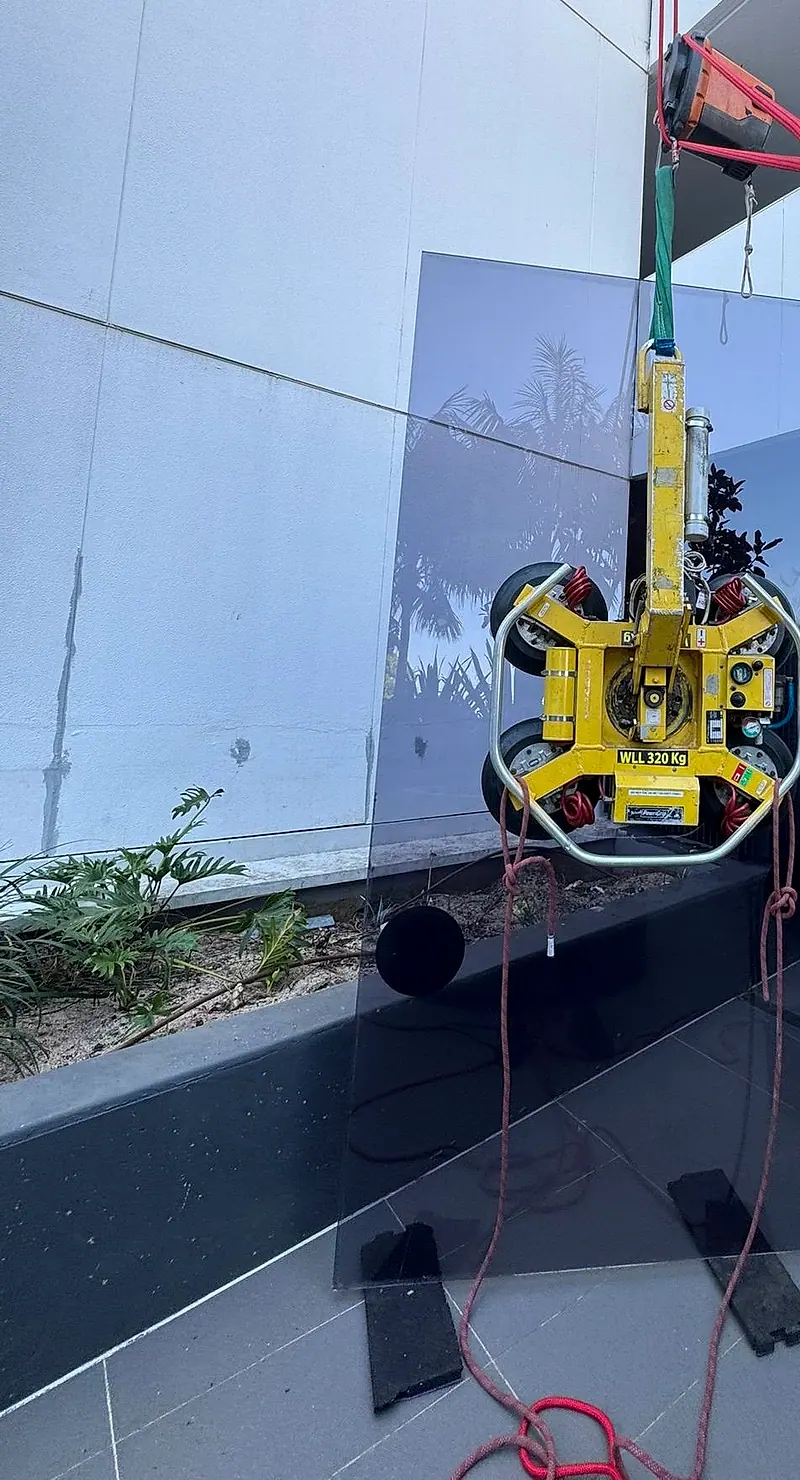 Glass panel lifted into position with a vacuum lifter on a high-rise balcony