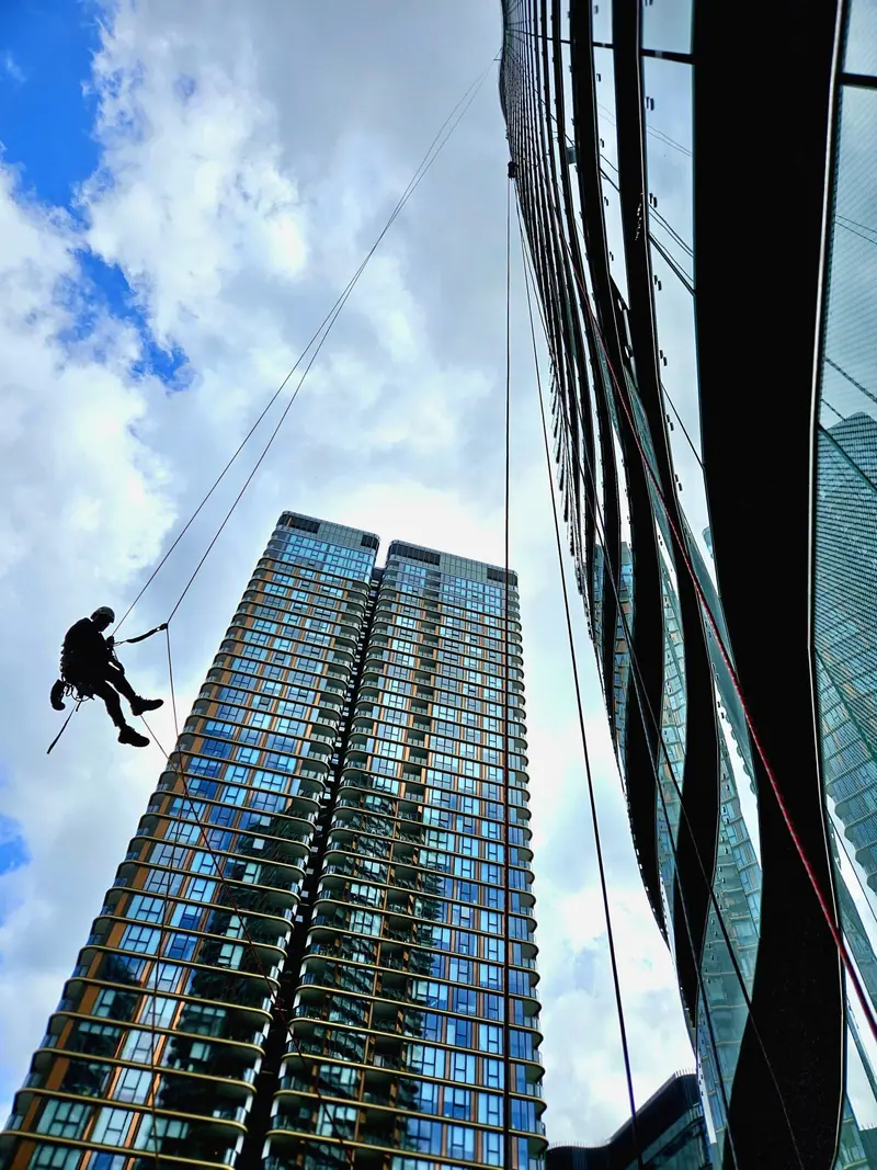 Technician descending beside a glass residential tower