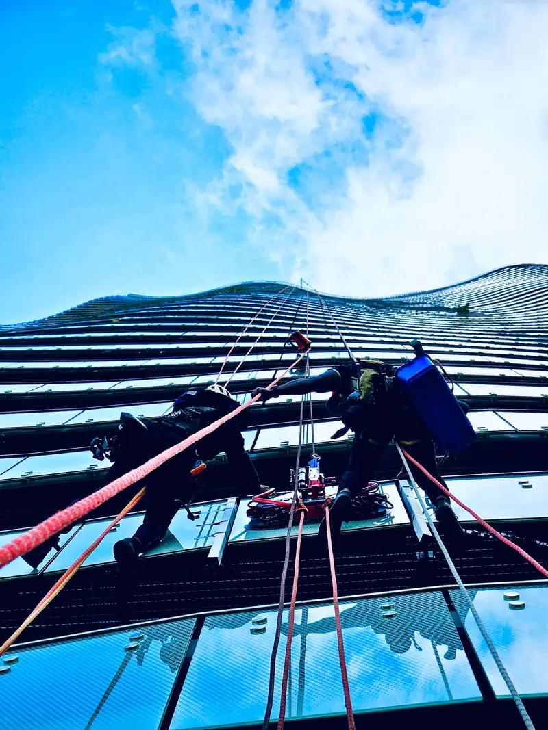 Technicians installing a glass panel on a curved high-rise facade