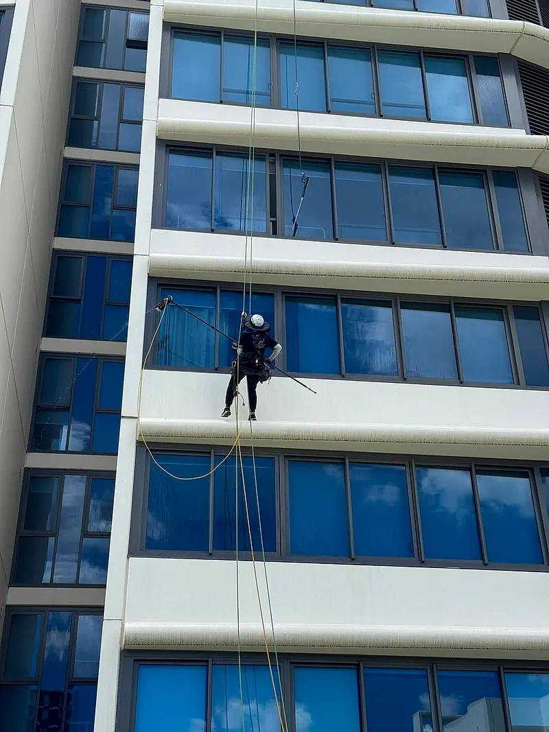 Technician on ropes working on a white apartment facade